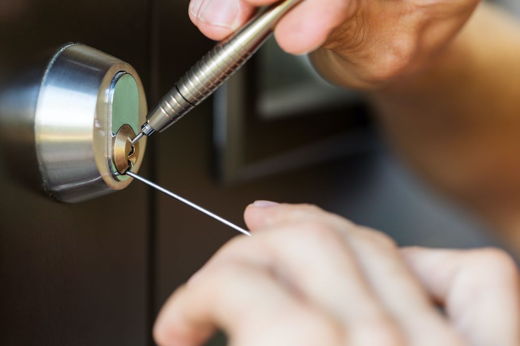 Locksmith working on a door lock cylinder with professional tools