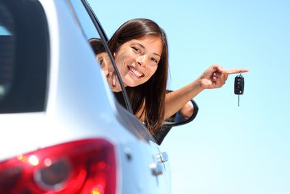 Smiling driver holding up car keys from her vehicle window